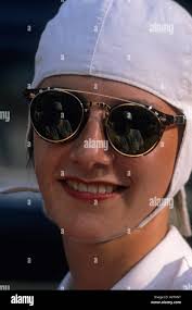Girl driver of vintage car . She wears retro dark glasses a white helmet  Stock Photo