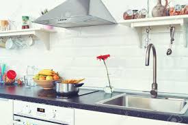 | home interior, kitchen decoration. Interior Of A Light Kitchen In The Apartment Bright Home Interior Decoration Items Fruit Flowers In A Pot Steel Hood Bright Ready Made Picture For Your Individual Design Stock Photo Picture And Royalty