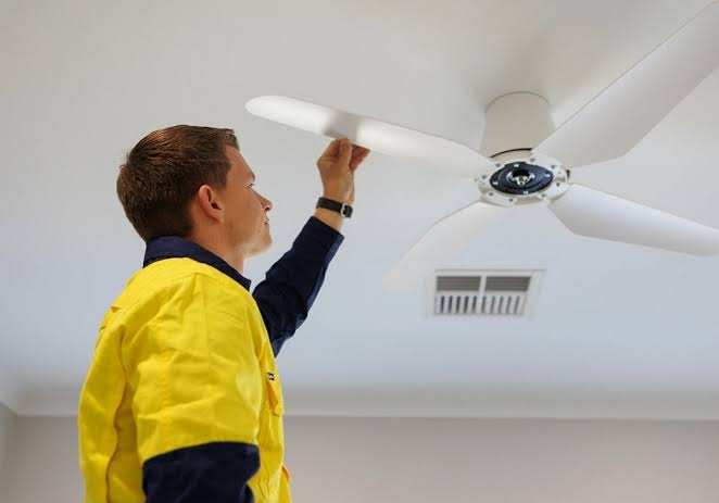Professional fitter installing a ceiling fan and downlights in Erith