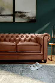 08 a brown chesterfield sofa in a living room with dark green walls and luxe gold accessories
