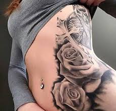 A rosary tattoo, which is usually paired with a cross can be a perfect mark to two roses and a long rosary beads with a beautifully done cross. Grey Ink Cross And Roses Tattoo On Left Side Rib