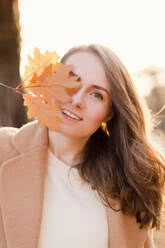 Portrait of teenage girl wearing wool cap and gauntlets leaning at tree  stock photo