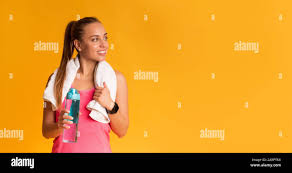 Sporty Woman With Bottle Of Water And Towel Wrapped Around Neck Stock Photo  - Alamy