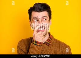 Photo of foolish nerd guy finger nose look empty space wear glasses brown  sweater isolated yellow background Stock Photo