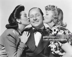 A content Robert Benchley receives kisses from Rosalind Russell and... News  Photo