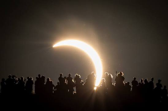 The sun's corona visible behind the moon during a total solar eclipse over the European landscape.