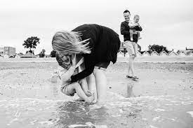 Asian couple watching her daughter play in the ocean. Family Portrait Photographer On Mersea Island Jasmine Jade Photographyjasmine Jade Photography