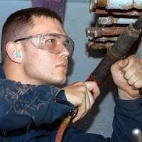 Operations Specialist 3rd Class Eric Martin uses a needle gun to remove old  paint