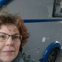 A blue vw bus parked in a field. Volkswagen panel van.