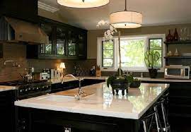 White kitchen cabinets across from a black kitchen island topped with marble countertops in a transitional kitchen design. Black Kitchen Cabinets With White Marble Countertops Contemporary Kitchen Jeff Lewis Design
