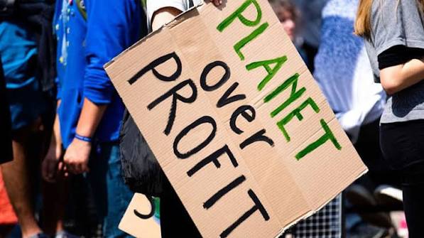 Protest sign reading “Planet over profit,” calling for environmental protection over financial gain.