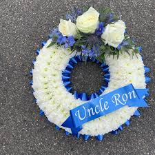 Available in a variety of designs, flower choice and colours. Blue And White Wreath Funeral Flowers Tribute With Personalised Ribbon Funeral Flowers Funeral Floral Arrangements Funeral Flower Arrangements