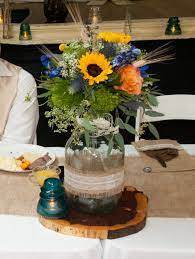 Moonshine Jug Centerpiece With Sunflowers Roses Blue Delphinium Queen Anne S Lace Green Tricks Wheat And S Jug Decor Blue Delphinium Rose Centerpieces