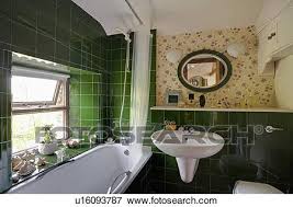 A green primary bathroom is a great way to design your space by bringing an outdoorsy, natural color into your home. White Bath Below Window In Small Bathroom With Green Wall Tiles And Patterned Wallpaper Stock Photo U16093787 Fotosearch
