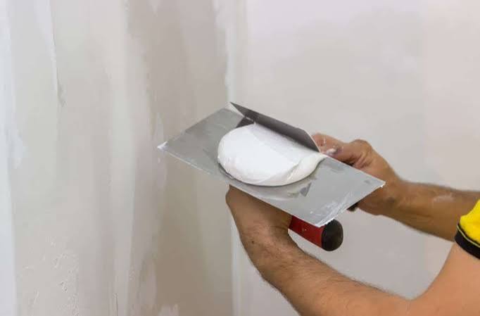 Application d'enduit de façade sur un mur extérieur — technicien taloche à la main