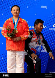 Silver medalist from China, Liu Yadong, left, poses while Park Byung-taek  of South Korea makes his way up the podium during the medal ceremony of the  mens 25-meter pistol individual shooting event