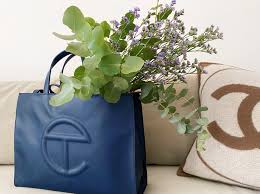 It's a status symbol that doesn't actually demand pecuniary status. Telfar Telfar Navy Medium Vegan Leather Shopping Bag Grailed