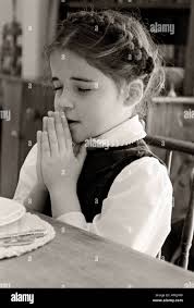 SOUTH CAROLINA ROCK HILL Black and white vintage photo of young girl with  braids saying the blessing before eating Stock Photo