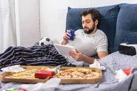 Handsome Loner Using Tablet And Holding Drink On Bed In Bedroom Stock Photo Dissolve