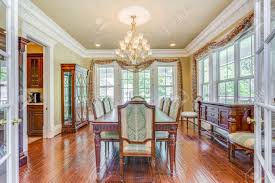 This is an elegant formal living room with white leather sofas and cushioned armchairs paired with contrasting black and blue pillows that go well with other accents of the room with a blue tone like the paintings on the light gray walls and the large one above the white mantle of the fireplace. Elegant Formal Dining Room With Retro Details And Big Windows Stock Photo Picture And Royalty Free Image Image 108106288