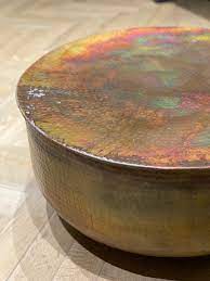 This attractive design hammered copper coffee table mixes the black square of the forged base with the rounded curves of the tack hammered copper top. Round Hammered Copper Table The Main Company