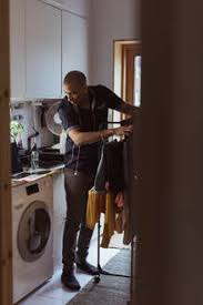 Your washing machine room stock images are ready. Man Looking At Washing Machine While Doing Laundry Chores In Utility Room Stockphoto