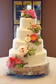 Placing fresh flowers into a cake without sealing them can cause toxic chemicals (like pesticides) to leach into the cake and potentially cause a major food hazard to your guests. White Wedding Cake With Cascading Fresh Flowers Rose Bakes