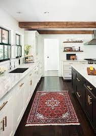 In the photo above, red kitchen decor is placed on the countertops and in glass display. Well Appointed Black And And White Kitchen Features A Red Wood Rug Placed In Front Of White Shaker Cabinets A Kitchen Design White Kitchen Design Home Kitchens