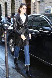 Kaia Gerber Wearing Cropped Raw Hem Kick Flare Jeans A White Top A Leather Belted Trench Coat Black Leather Kick Flare Jeans Outfit Fashion White Top Jeans
