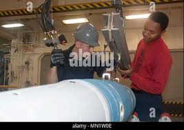Aviation Ordnanceman 2nd Class Travis Smith, from Indianapolis, center, and  Mineman 3rd Class Clifton Cook, from Clarendon, Ark., right, assigned to  Navy Munitions Command East Asia Division (NMC EAD) Unit Misawa, disassemble