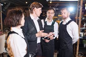 Confident Restaurant Manager Discussing Seating Chart With Waiter