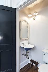 A Glossy Blue Door Opens To A Tiny Vintage Powder Room Boasting A White Distressed Vanity Mirror Mounted On Tiny Powder Rooms Powder Room Small Trendy Bathroom