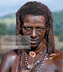 A Maasai warrior resplendent with long ochred braids. His body has been  smeared with red ochre mixed with animal fat while parts of his face have  been covered with ochre powder. -