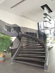 Frameless glass bannister face fixed to timber staircase with a stainless steel handrail fixed to both the glass and the upper section of wall. Curved Glass Balustrade Commercial Staircase Demax Arch