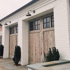 Black And White House With Wood Garage Door Black Windows On Wood Doors For A White House Wood Doors Wood Garage Doors Wood Walls Living Room