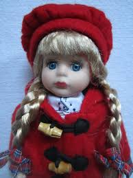 Porcellänsdocka med röd kappa