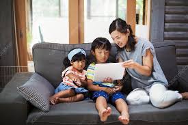Woman, boy, young girl on grey sofa with digital tablet - Stock Image -  F021/7556 - Science Photo Library