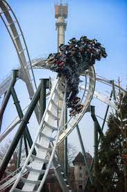 Passagiers nemen plaats in een van de twee treinen en zitten in bakjes die naast de baan hangen, zonder dat zij een vloer onder zich hebben. Foto Heide Park Resort Flug Der Damonen Heide Park Freizeitpark Achterbahn