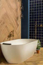 speels gebruik van houtlook tegels op de wand geven deze badkamer met vrijstaand bad en geborsteld gouden kranen badkamer badkamer vloertegels badkamer ontwerp