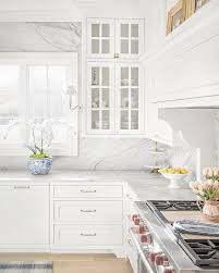 Modern farmhouse kitchen with white cabinets and dark wood floor. Benjamin Moore Oc 117 Simply White Kitchen With White Carrara Marble Slab Backsplas Classic White Kitchen Marble Countertops Kitchen Kitchen Backsplash Designs