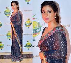 In the instagram image, kajol is seen draped in an orange printed saree and sleeveless blouse with her hair open, next to a window. Kajol Devgan In Patine Saree South India Fashion Elegant Saree Kajol Saree Saree Designs