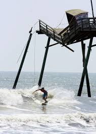 a surfer passes the broken end of the bogue inlet fishing