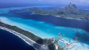 A cluster of tiny islands, floating in the middle of the ocean, surrounded by coral reefs and gentle waves. Bora Bora The Problem With Paradise Conde Nast Traveler
