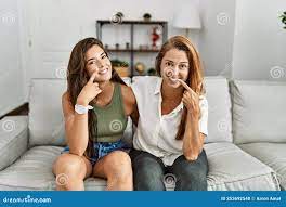 Mother and Daughter Together Sitting on the Sofa at Home Pointing with Hand  Finger To Face and Nose, Smiling Cheerful Stock Photo - Image of fingers,  face: 253692540