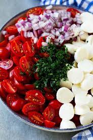 A Bowl Of Halved Cherry Tomatoes Mozzarella Balls Herbs And Minced Red Onion Cherry Tomato Salad Tomato Salad Recipes Tomato Mozzarella Salad