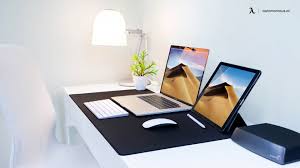 Small minimalist white home office with dark wooden shelves, stylish furniture in neutral colors, and a colorful painting for a pump of energy to the room. Minimalist Home Office Design Simple Yet Stylish