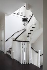 A sisal runner leads the way for guests on this smart, traditional staircase. White Staircase With Brown Hand Rail Transitional Entrance Foyer