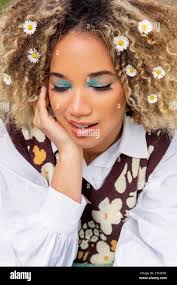 High angle of ethnic young woman with curly blonde hair looks down while  resting her chin