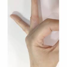 Let's talk about finger tattoo designs. White Ink Cross Tattoo On The Finger