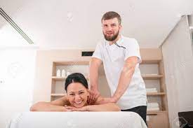 Cheerful Middle-aged Adult Female Getting A Massage In Wellness Center.  Massagist And Patient Looking At Camera With Smile. Low Angle Stock Photo,  Picture and Royalty Free Image. Image 94516986.